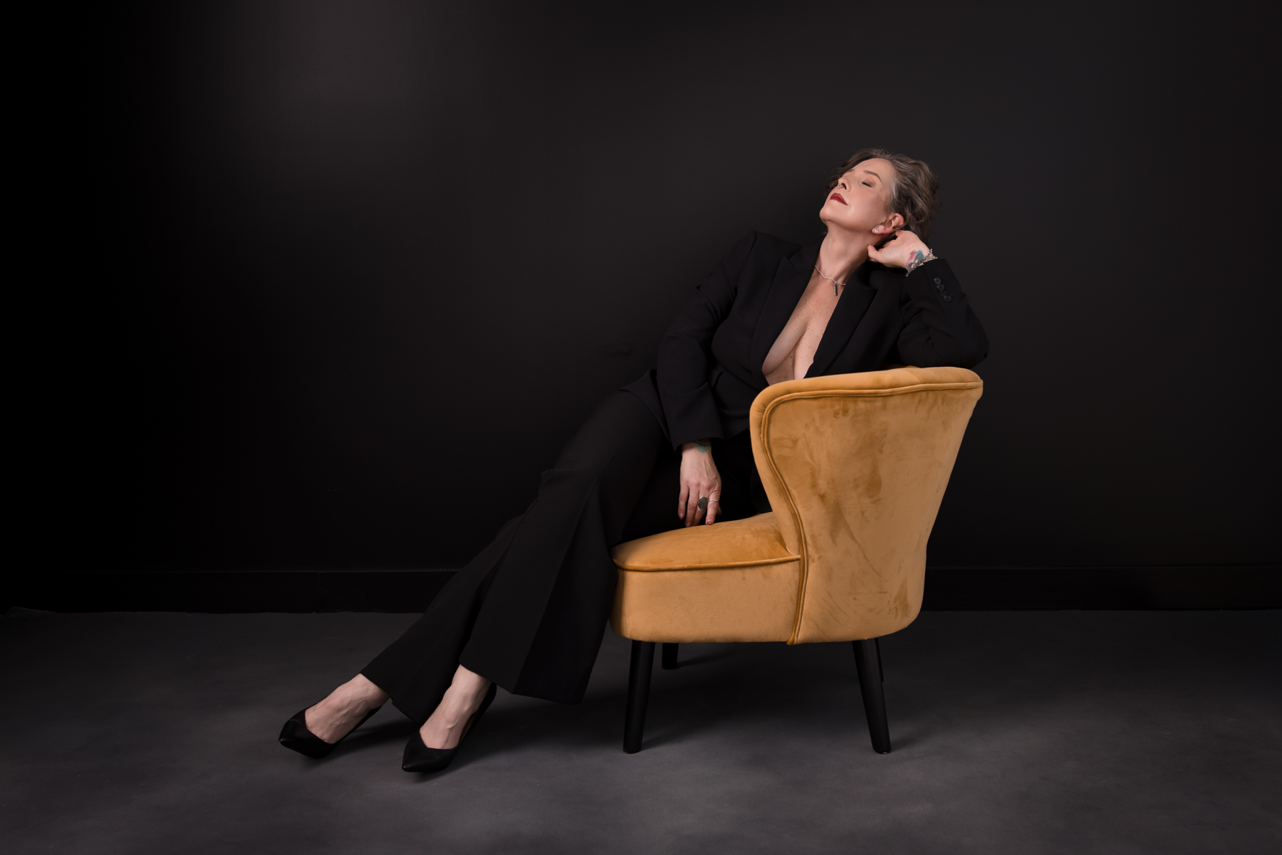 executive-boudoir-photoshoot-sonoma-county woman tilting head back sitting in chair